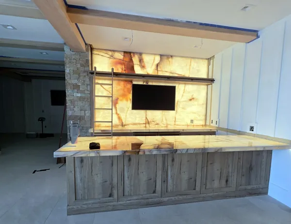 Home bar with a backlit onyx wall, oak cabinetry, wood beams and paneled walls, Tampa Bay